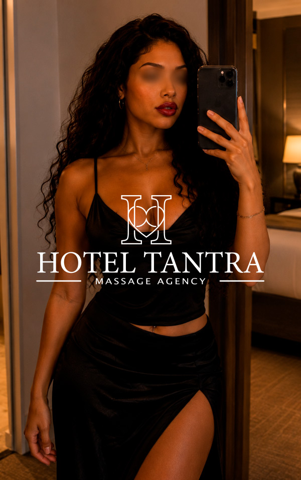Promotional photo of a woman in a hotel room taking a selfie, with the words 'Hotel Tantra' and 'Massage Agency' overlaid as branding.